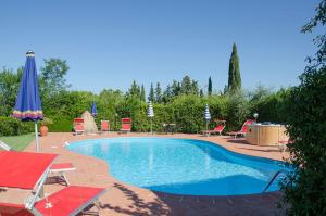 a swimming pool with chairs and an umbrella at Il Cielo in Terra: Il Podere in Montaione