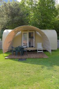 a tent with a table and chairs in a yard at Camping Alpino - Nature Village in Malcesine