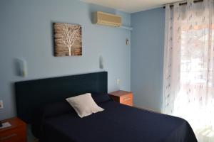 Dormitorio azul con cama y ventana en Hotel L'Escala, en Cullera