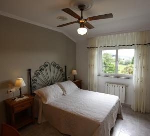 a bedroom with a bed with a ceiling fan and a window at Casa Guillermo apartamentos turísticos in Barreiros