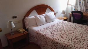 a hotel room with a bed and a telephone at Hostal Continental in Vigo