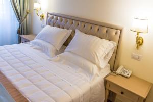 a bed with white sheets and a phone on a table at Relais Paradiso Resort & Spa in Gualdo Cattaneo