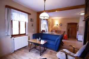 a living room with a blue couch and a table at Ubytovani U Lavky in Suchovršice