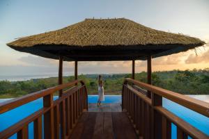a woman standing on a wooden bridge with a large umbrella at Semabu Hills Hotel Nusa Penida in Nusa Penida