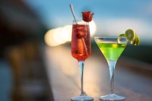 two cocktails sitting on a wooden table with a lime and sidx sidxktop at Semabu Hills Hotel Nusa Penida in Nusa Penida