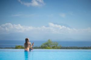 a woman sitting in the water in a pool at Semabu Hills Hotel Nusa Penida in Nusa Penida