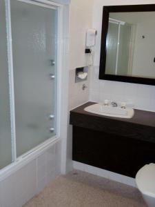 a bathroom with a sink and a shower with a mirror at West Coaster Motel in Queenstown