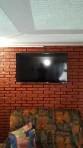 a flat screen tv on a brick wall with a couch at Vila D&D in Zlatibor