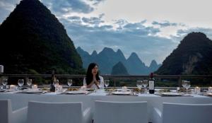 a woman sitting at a table with wine glasses at Zen Box House in Yangshuo