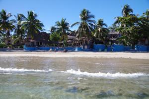 una spiaggia con palme e case sullo sfondo di Villa Valiha Boutique Hotel ad Ambatoloaka