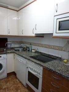 a kitchen with white cabinets and a sink and a microwave at Apartamento Jardines del Sella in Cangas de Onís