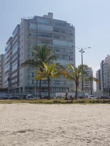 a beach with palm trees and a large building at Boulevard Family Club in Bertioga