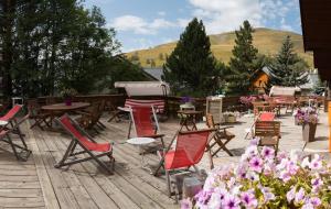 a bunch of chairs and tables on a deck with flowers at Hotel Adret in Les Deux Alpes