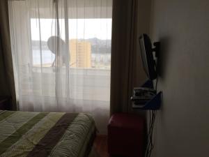 a bedroom with a bed and a window with a view at Pronejoet Departamentos La Herradura in Coquimbo