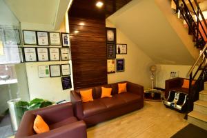sala de estar con sofá marrón con almohadas de color naranja en MY Bizz Hotel Sapna, en Pune
