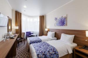 カザンにあるRaymond Hotelのベッド2台とデスクが備わるホテルルームです。