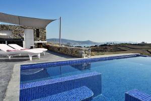 - une piscine avec 2 chaises longues et une maison dans l'établissement Magic Krios, à Parikia