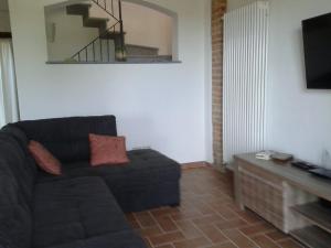 sala de estar con sofá negro y TV en Casa Vacanze Sweet Dreams, en Agliano Terme
