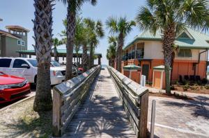 a wooden walkway with palm trees and a building at Beachside Inn in Destin