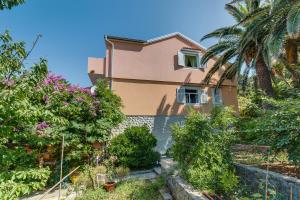 a house with trees and plants in front of it at Apartments Pepi in Mali Lošinj