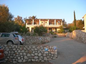 a house with a stone wall and a car parked in front at To Ampelaki in Tsoukalades
