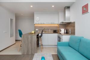 a kitchen and a living room with a blue couch at 8ERA Business Executive Rotermanni Apartments in Tallinn