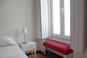 a bedroom with a red bench and a window at Huga Home in Lamego