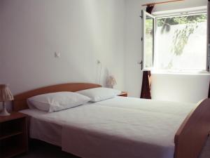 a bedroom with a white bed and a window at House Baglija in Lumbarda