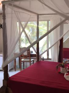 a bedroom with a canopy bed with a window at Crystal Bay Resort in Watamu