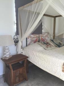 1 dormitorio con 1 cama y 1 mesa con lámpara en Les Gîtes de CASITA By kreyol animal, en Grand-Bourg