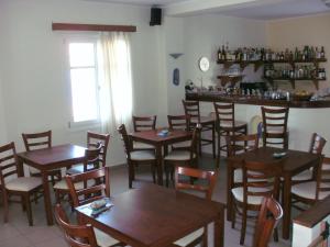 a restaurant with wooden tables and chairs and a bar at Miké Hotel in Aegiali