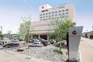 a building with cars parked in a parking lot at Hotel Granmirage in Uozu