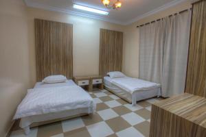 a bedroom with two beds and a checkered floor at Star City Chalets in Az Zulfi