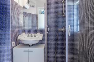 a bathroom with a sink and a shower with blue tiles at Monte & Paradiso in Pula
