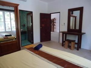 1 dormitorio con 2 espejos, 1 cama y 1 mesa en Samui Manor House Apartments, en Ban Bang Po