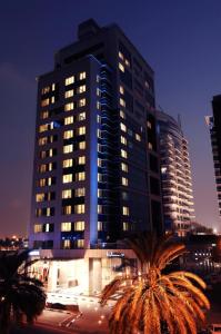 a tall building with palm trees in front of it at Samaya Hotel Deira in Dubai