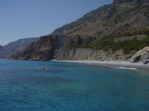 a body of water with a beach and a mountain at Samaria in Agia Roumeli