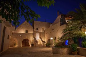 un gran edificio de piedra con patio por la noche en Agriturismo Masseria Casa Busciana, en Alberobello