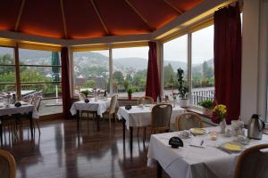 un ristorante con tavoli, sedie e ampie finestre di Panoramahotel Berghof a Baiersbronn
