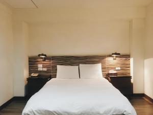 a bedroom with a large white bed with two pillows at Hua Tai Hotel in Hsinchu City