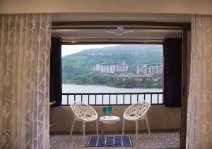 a balcony with two chairs and a table and a window at Lavasa Luxury Lakeview Studio in Lavasa