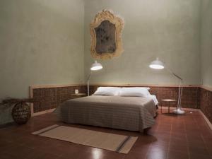 um quarto com uma cama, 2 candeeiros e um espelho em Antico Convento San Francesco em Bagnacavallo