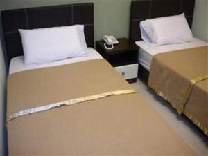 two beds in a hotel room with a phone at BBP Hotel in Kota Bharu