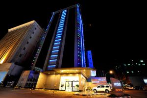 wysoki budynek z niebieskimi światłami w nocy w obiekcie Hyatt Buyutat w Rijadzie