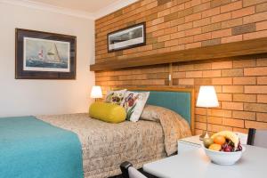 a hotel room with a bed and a bowl of fruit on a table at Ningana Motel in Mudgee