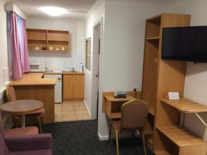 a room with a kitchen with a desk and a table at Edgecliff Lodge Motel in Sydney