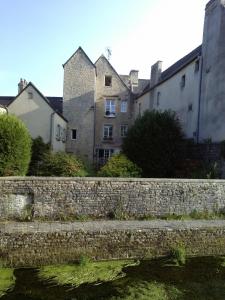 un vieux mur en pierre devant certains bâtiments dans l'établissement L'AURE BLEUE, à Bayeux