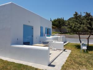 a white villa with a blue door and a yard at Sarakiniko Rooms in Adamantas