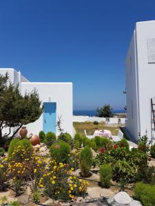 a garden in front of a white building with flowers at Sarakiniko Rooms in Adamantas