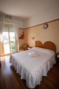 ein Schlafzimmer mit einem großen Bett mit einer weißen Tagesdecke in der Unterkunft Hotel Britannia Rimini Marina centro in Rimini